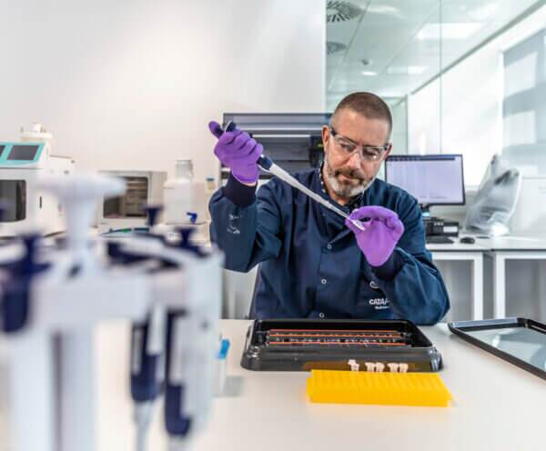 Man in a lab coat with a pipette