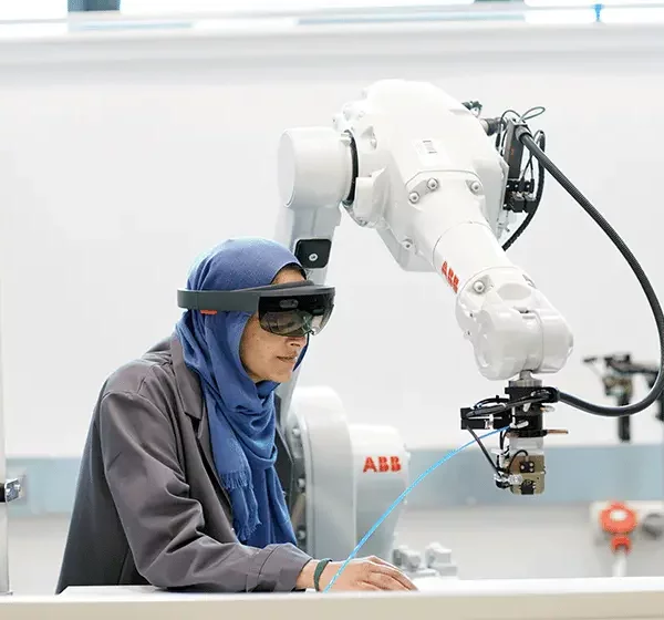 Women wearing safety goggles working with a robotic arm